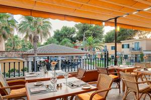 Außenterrasse des Occidental Playa de Palma Hotels mit gedeckten Tischen und Sonnenschirm.
