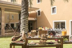 Frühstücksbuffet im Freien vor dem Occidental Playa de Palma Hotel mit Obst, Brot und Getränken.