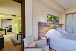 Ein modernes Hotelzimmer im Occidental Playa de Palma mit einem Bett, Nachttisch, Lampe und Panoramafenster.