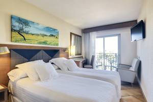 Doppelzimmer im Occidental Playa de Palma mit zwei Betten, einem Fernseher, einem Schreibtisch und einem Balkon.