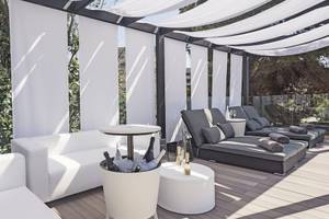 Terrasse des Occidental Playa de Palma mit weißen Lounge-Möbeln, Sonnenliegen und weißen Vorhängen.