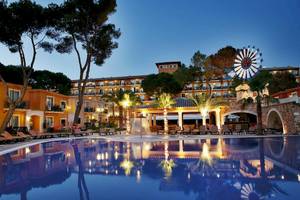 Abendansicht des Swimmingpools des Occidental Playa de Palma Hotels mit Loungestühlen und Bäumen