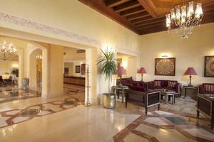 Lobby des Steigenberger Coraya Beach Hotels mit Kronleuchtern, Sofas und Pflanzen.