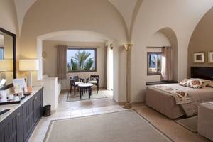 Innenansicht eines eleganten Zimmers im Steigenberger Coraya Beach Hotel mit Bett, Schreibtisch und Ausblick.