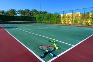 Tennisplatz im Steigenberger Coraya Beach Hotel mit zwei Tennisschlägern und Tennisbällen.