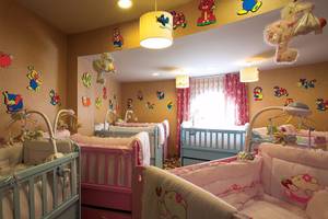 Kinderzimmer im Cornelia Diamond Golf Resort & Spa mit farbenfrohen Wandaufklebern und mehreren Babybetten.