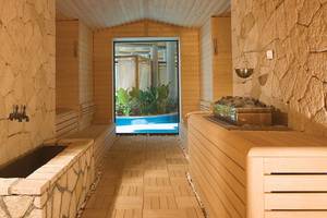 Innenansicht der Sauna im Cornelia Diamond Golf Resort & Spa mit Holzwänden und einem Durchgang zum Pool.