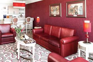 Wohnzimmer im Cornelia Diamond Golf Resort & Spa mit rotem Ledersofa, Esstisch und Dekor.