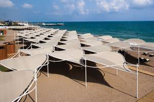 Luftaufnahme des Cornelia Diamond Golf Resort & Spa Strandes mit vielen weißen Sonnenschirmen