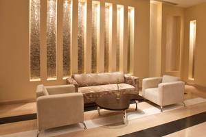 Hotellobby mit gemustertem Sofa und weißen Sesseln neben einer runden Tisch.