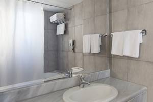 Badezimmer im Hotel Atlantica Mikri Poli auf Rhodos mit Spiegel, Waschbecken und Handtüchern.