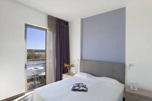 Hotelzimmer im Atlantica Mikri Poli Rhodes mit Blick auf eine Terrasse und Meer.