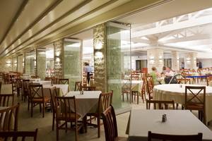Restaurant des Atlantica Mikri Poli Rhodes Hotels mit vielen Tischen und Stühlen.