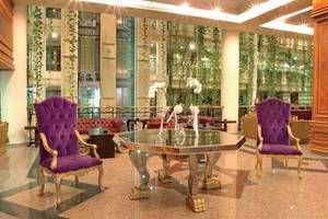 Lobby des Constantinos the Great Beach Hotels mit einem Glastisch und zwei violetten Stühlen.