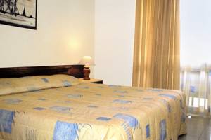 Schlafzimmer im Kenya Bay Beach Hotel mit einem Bett, Nachttisch und Lampe.