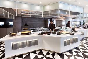 Restaurant-Innenbereich des Hotels Tigotan Lovers & Friends mit schwarzen und weißen Bodenfliesen und weißen Tischen.