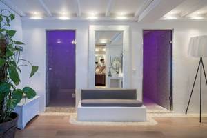 Saunabereich im Katikies Chromata Hotel auf Santorini mit einer Bank, zwei Türen und einer Pflanze.