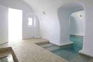 Innenansicht des Badezimmers im Katikies Chromata Hotel auf Santorini mit weißen Wänden und einem kleinen Pool.