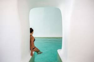 Frau im Pool von Katikies Chromata Santorini, die aus dem Wasser kommt