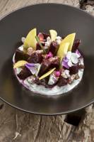 Beetroot-Platte mit verschiedenen Toppings auf einem schwarzen Teller.