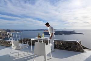 Mann auf einer Terrasse mit Blick auf das Meer, serviert ein Getränk.