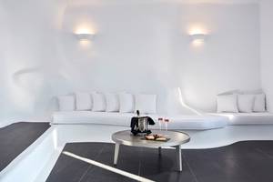 Loungebereich des Katikies Chromata Santorini Hotels mit weißen Möbeln und schwarzem Boden.