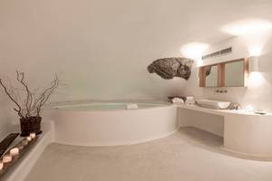 Weißes Badezimmer im Katikies Chromata Santorini Hotel mit einem großen Whirlpool und einem Waschbecken.