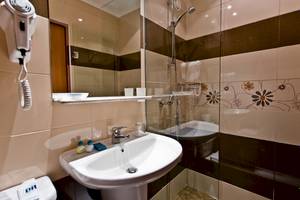 Badezimmer im DIT Evrika Beach Club mit Waschbecken, Spiegel und Haartrockner.