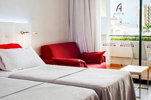 Doppelzimmer im Alexandre Hotel Gala mit zwei Betten, rotem Stuhl und Balkon.