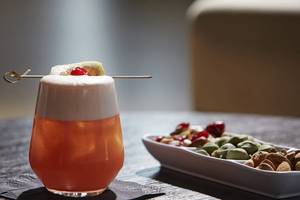 Exklusives Cocktail im Daios Cove Luxury Resort & Villas mit Dekoration und Snacktablett im Hintergrund.
