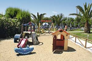 Kinderspielplatz im Poseidon Beach Hotel mit Sand, Spielgeräten und Sonnenschirmen.
