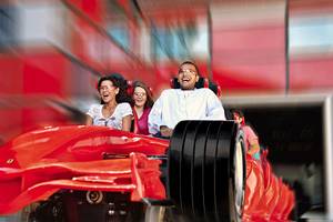 Gruppe von Gästen im roten Ferrari-Rennwagen im Crowne Plaza Abu Dhabi Yas Island Hotel