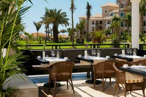 Außenterrasse des Gran Melia Palacio de Isora Hotel mit Blick auf eine gepflegte Landschaft und Gebäude.
