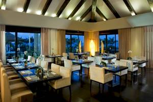 Restaurantbereich des Gran Melia Palacio de Isora mit gedeckten Tischen und Stühlen.