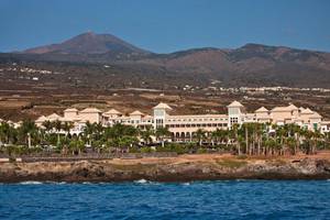 Außenansicht des Gran Melia Palacio de Isora Hotels mit Blick auf das Meer und die Berge.