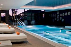 Innenpool-Lounge des Gran Melia Palacio de Isora mit weißen Liegen und Wasserfontäne.