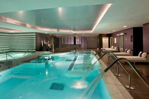 Innenpool des Gran Melia Palacio de Isora Hotels mit blauem Wasser und Lichteffekten.