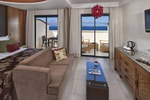 Gran Melia Palacio de Isora Suite Zimmer mit Meerblick, großes Bett, Couch, Tisch, Fernseher und Balkon.