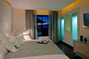 Schlafzimmer Ansicht im Gran Melia Palacio de Isora Hotel mit Bett, Nachttisch und Fernseher.