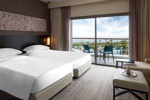 Doppelbett-Zimmer im Hyatt Place Taghazout Bay mit Blick auf den Pool und die Landschaft.