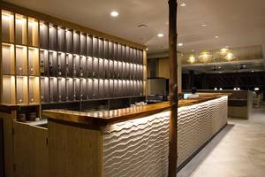 Innenansicht der Bar im Andaman Cannacia Resort mit Holztheke und beleuchteten Regalen.
