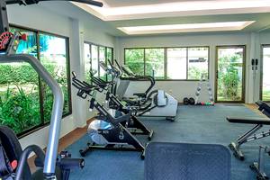 Fitnessraum im Andaman Cannacia Resort mit Cardiogeräten und Fenstern.