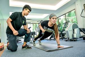 Fitnesstrainer und Kundin im Fitnessstudio des Andaman Cannacia Resorts