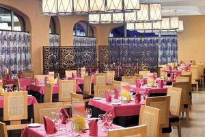 Restaurant im Barcelo Maya Palace Hotel mit vielen gedeckten Tischen und dekorativen Elementen.