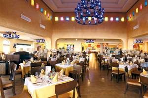 Restaurant des Barcelo Maya Palace Hotels mit vielen gedeckten Tischen und bunten Kronleuchtern.
