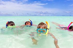 Vier Kinder tauchen im klaren Wasser der Malediven, Innahura Maldives Resort