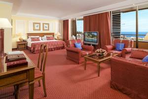 Innenansicht der Botanico & The Oriental Spa Garden Suite mit Meerblick, roten Möbeln und Fernseher.