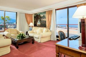 Wohnzimmer mit Meerblick im Botanico Hotel mit Sofas, Tisch, Lampe und Gemälde.