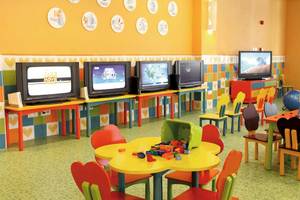 Kinderspielzimmer im Barcelo Maya Palace mit bunten Möbeln, Fernsehgeräten und Spielzeug.