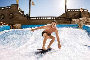Ein Mann surft auf einer künstlichen Welle im Wasserpark des Barcelo Maya Palace.